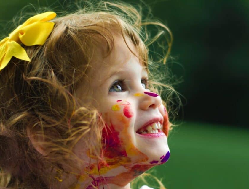 Little girl at a child care center with paint on her face.